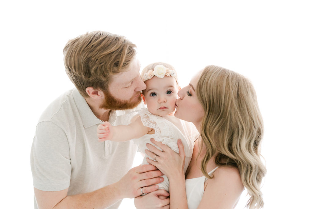 mom and dad kissing baby